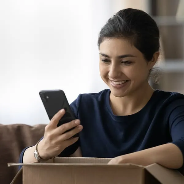 Mujer sonriente sosteniendo un teléfono celular.