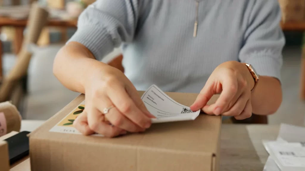 Una mujer coloca un papel en una caja, mostrando un acto de organización o envío de documentos.